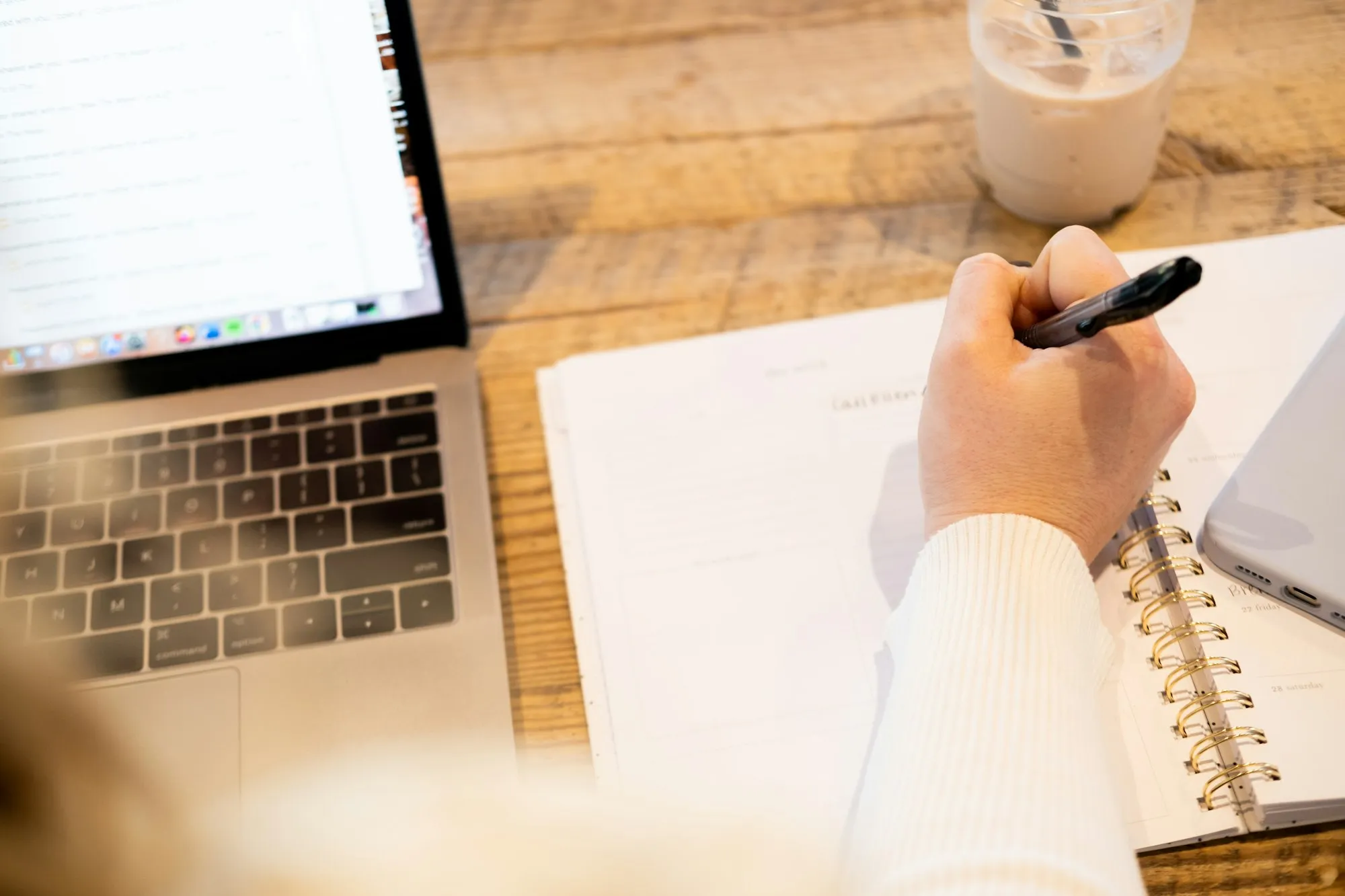 Person writing notes next to a laptop while job hunting